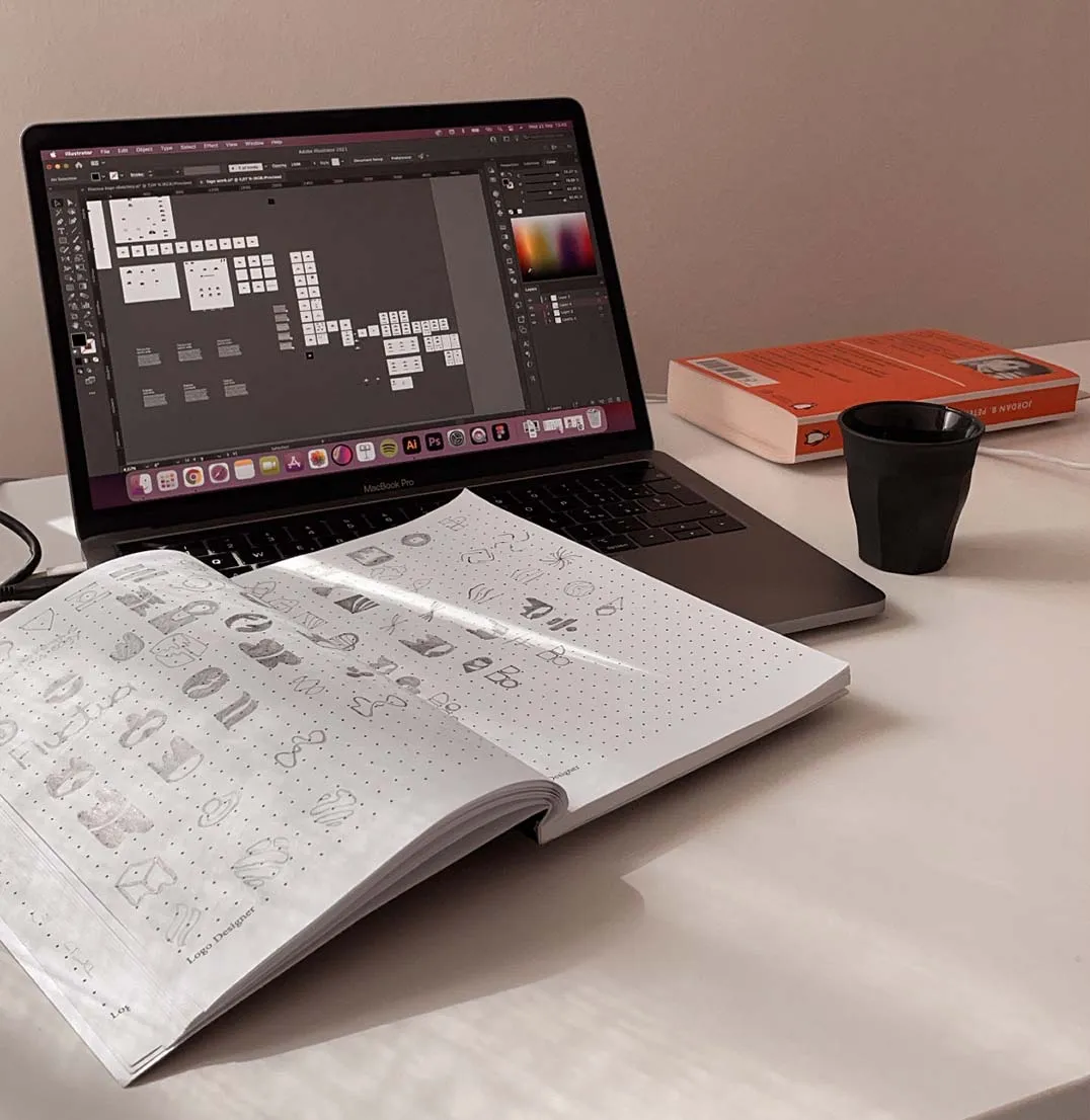 Notebook, laptop, espresso cup, and book on a desk